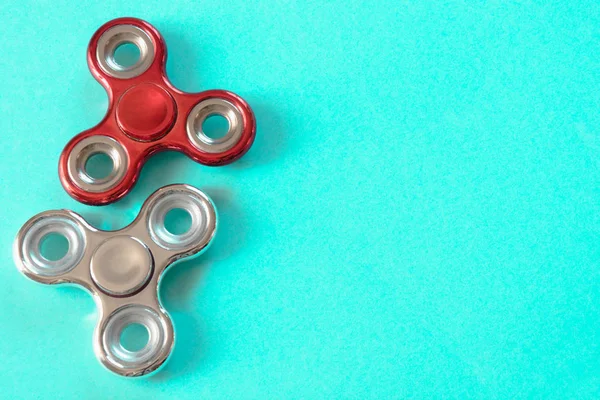 Gümüş ve kırmızı parlak parmak spinner stres kıpır. Düz mavi üzerinde yatıyordu.