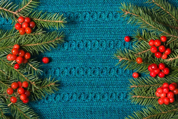 Tanne und rote Beeren aus Viburnum als Rahmen auf Strickpullover Hintergrund. Weihnachtskonzept. flache Lage. — Stockfoto