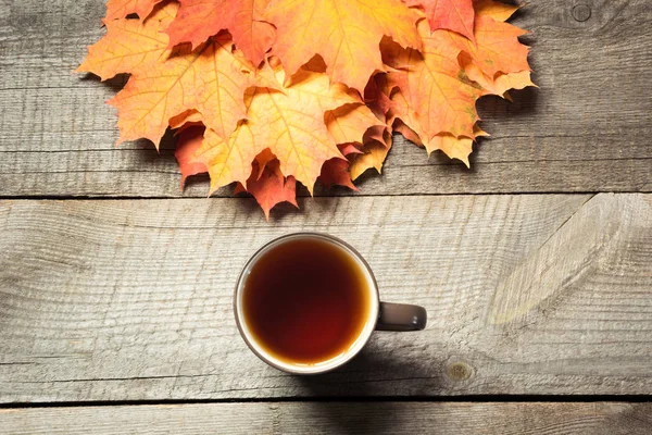 Fincan çay, ahşap tahta üzerinde renkli sonbahar yaprakları. Sonbahar natürmort, vintage tarzı.