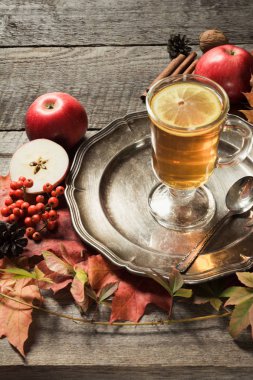 Cam bardak çay sonbahar yaprakları ve elma ahşap bir vintage tahtada bir dekor ile ısınma. Sonbahar.