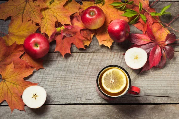Quente xícara de chá, decoração de folhas de outono, maçãs na tábua de madeira. Cair ainda vida. Vista superior . — Fotografia de Stock