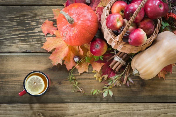 Wärmende Tasse Tee, Dekor der Herbsternte, Kürbis, Äpfel auf Holzbrett. Sturz. Stillleben. Ansicht von oben. — Stockfoto