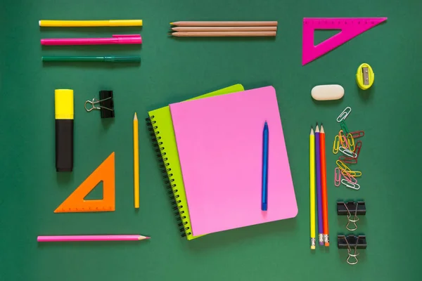 Színes iskolai kellékek, rózsaszín könyv a zöld. Felülnézet, lapos feküdt, másol hely. — Stock Fotó