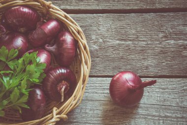 Rustik ahşap tahta üzerinde sepet içinde kırmızı soğan