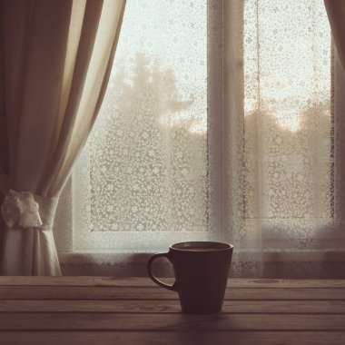 Fincan sade kahve ya da çay ahşap masa üstünde belgili tanımlık pencere önünde. Uzay kopyalayın. Romantik günbatımı.