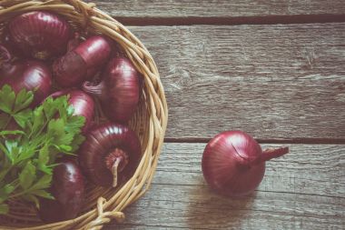 Rustik ahşap tahta üzerinde sepet içinde kırmızı soğan