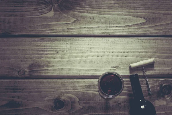 Bir cam şişe kırmızı şarap açmak, bir ahşap arka plan üzerinde düşünüp. Kopya alanı ve üstten görünüm.