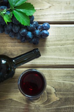 Açık bir şişe kırmızı şarap cam, tirbuşon ve ahşap bir gemide olgun üzüm ile. Kopya alanı ve üstten görünüm.