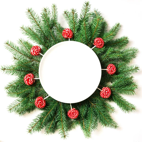 Ramas de árbol de Navidad y piruleta roja como decoración sobre un fondo blanco. Vista desde arriba . — Foto de Stock