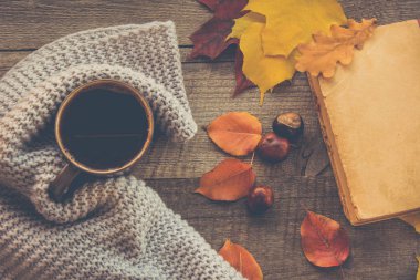 Kahve, rahat örme eşarp, sonbahar Kupası ahşap tahta üzerinde yapraklar