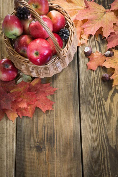 Sonbaharda hasat, elma sepeti, ahşap tahta üzerinde renkli sonbahar yaprakları. Sonbahar natürmort, vintage tarzı. Üstten Görünüm.