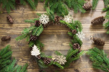 Çam dalları ve ahşap masa üzerinde dekoratif kar taneleri ile Noel çelenk. Düz yatıyordu.