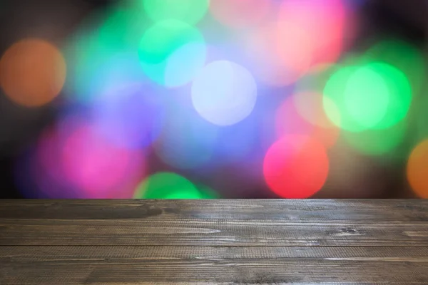 Blurred colorful garland and wooden tabletop as foreground. Image for display or montage your christmas products. — Stock Photo, Image