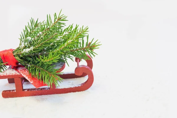 Árbol de Navidad sobre trineo rojo sobre fondo blanco. Copiar espacio. Tarjeta de día festivo. De cerca. . — Foto de Stock
