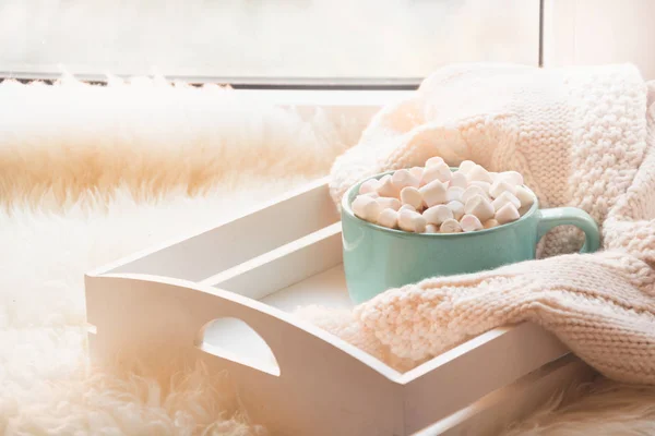 Blue cup of hot chocolate with marshmallow on white windowsill with furskin for rest. Holiday. — Stock Photo, Image