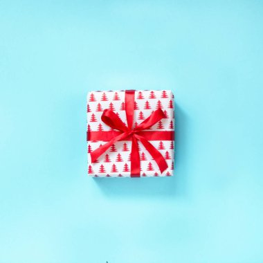 Mavi yüzeyi kırmızı kurdele ile Noel hediyesi. Üstten Görünüm. Kare.