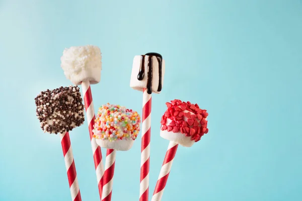 Zoete taai marshmallow op stro versierd met gesmolten chocolade en cake hagelslag op blauw. Kopieer ruimte. Kerstkaart. — Stockfoto