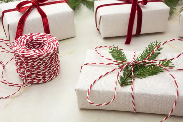 Caja de regalo de Navidad envuelta en papel artesanal blanco y cinta decorativa de cuerda roja en la superficie marmoreal. De cerca. . — Foto de Stock