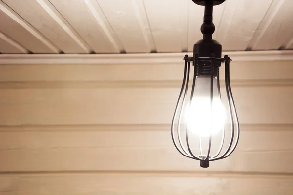 Eine schwarze Lampe unter der Decke in einem hölzernen Bauernhaus. — Stockfoto