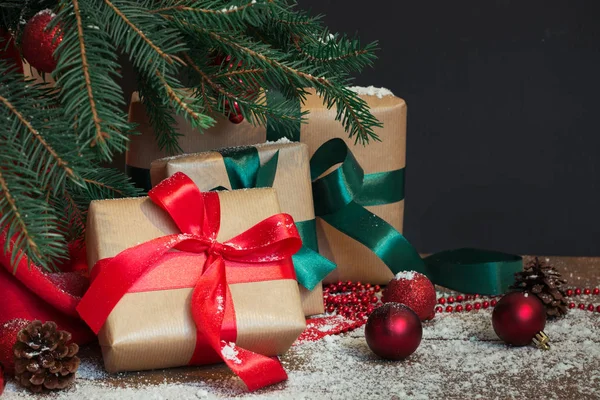 Fondo de vacaciones de Navidad. Regalos con una cinta roja, sombrero de Santa Claus y decoración bajo un árbol de Navidad en una tabla de madera . — Foto de Stock