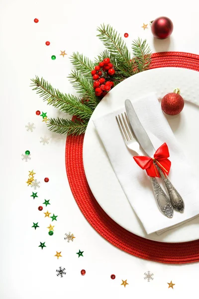 Christmas table setting with white dishware, silverware and red decorations on white background. Top view. — Stock Photo, Image