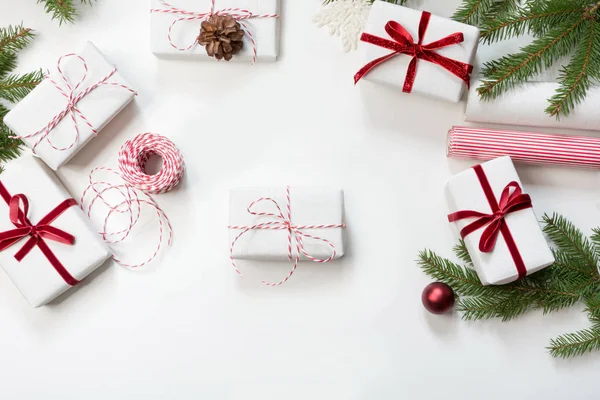 Noel hediye kutuları beyaz Kraft kağıt ve dekoratif kırmızı ip şerit beyaz yüzey üzerinde sarılı. Düz yatıyordu. Üstten Görünüm. — Stok fotoğraf