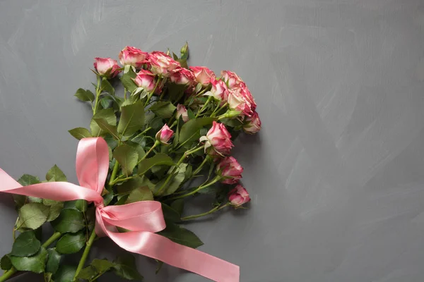 Ramillete de rosas rosas rosadas con cinta rosa sobre fondo gris. Vista superior. Tarjeta romántica con amor . — Foto de Stock