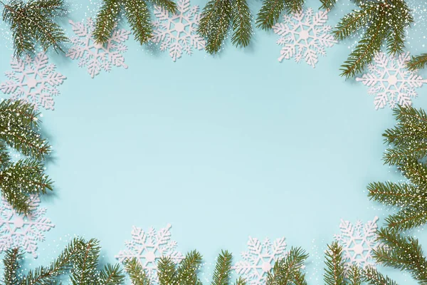 Borde creativo de Navidad con copos de nieve blancos y ramas sobre fondo azul. Acostado. Copiar espacio. Nieve dibujada . — Foto de Stock