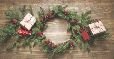 Çiçek çelenk, hediye kutuları, kırmızı dekor ahşap tahta üzerinde Noel bileşimi. Düz yatıyordu. Üstten Görünüm. Kopya alanı.