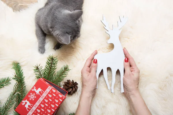 Mano femenina sosteniendo venado de juguete navideño. Concepto navideño. El invierno. Vista desde arriba . — Foto de Stock