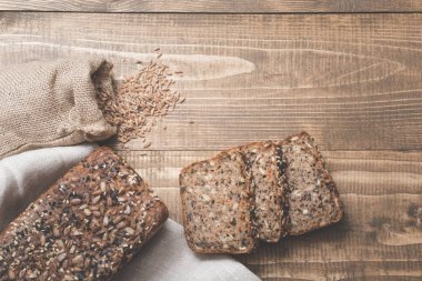 Dilimleri ile kesme ve bütün tahıl ekmeği bir ahşap tahta üzerinde. Kırsal gıda arka plan. Üstten Görünüm.