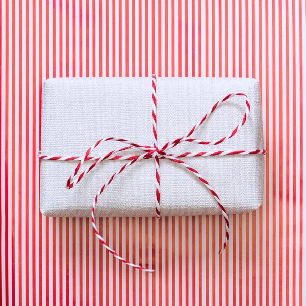 Christmas gift with red ribbon on stripes surface. Top view. Square. — Stock Photo, Image