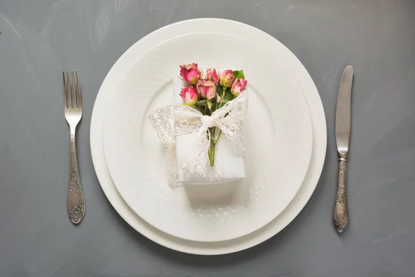 Святковий стіл, жіночий білий подарунок з квітами, вінтажний посуд, срібний посуд та прикраси на сірому. Вид зверху. Концепція . — стокове фото