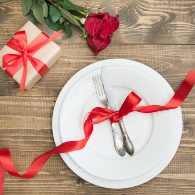 Romantik bir akşam yemeği kavramı. Ahşap arka plan üzerinde Sevgililer günü Festival Tablo ayarı. Kırmızı gül ve romantik hediye. Üstten Görünüm.