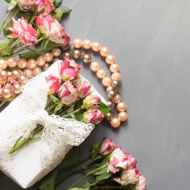 Kadın düz sahne gül çiçek, Hediyelik ve kolye nötr gri arka plan üzerinde yatıyordu. Üstten Görünüm.