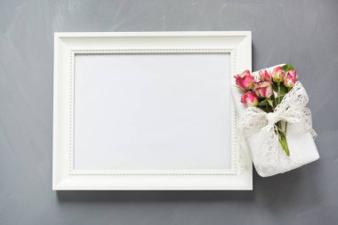 Kadın hediye ve gül nötr gri arka plan üzerinde beyaz fotoğraf çerçevelemek. Üstten Görünüm. Kopya alanı.