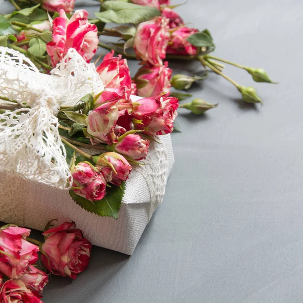 Mujer plana escena laica rosas frescas flores y regalo sobre fondo gris neutro. Vista superior. Copiar espacio . — Foto de Stock