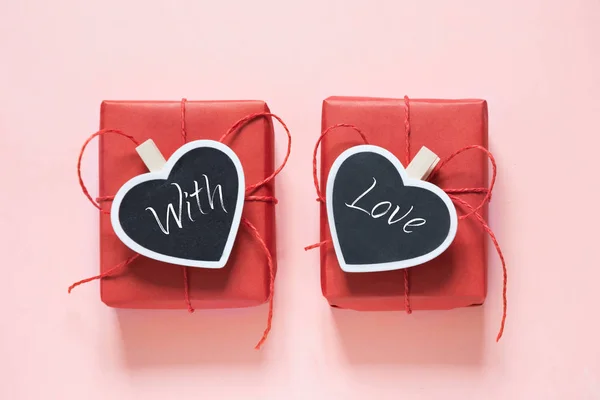 Composición San Valentín: dos cajas de regalo rojas con pinza como corazón con texto sobre pizarra sobre fondo rosa pastel. Vista desde arriba . —  Fotos de Stock