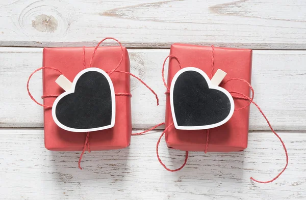 Tarjeta de San Valentín. Dos cajas de regalo rojas con pinza como corazón con espacio para texto sobre pizarra sobre fondo claro de madera. Vista superior . —  Fotos de Stock