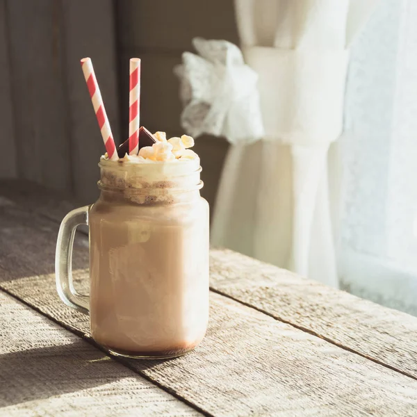 Schokoladen-Kaffee-Milchshake mit Schlagsahne, serviert in einem Glas auf grauem Holzgrund. Süßes Sommergetränk. quadratisches Bild. — Stockfoto