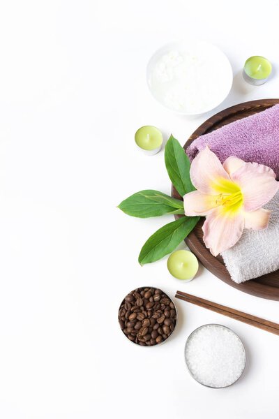 Spa setting of towel, flower, coffee on white. Copy space. Relax.