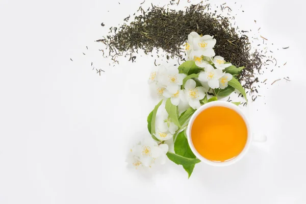Száraz jázmin zöld tea levelek friss jázmin virágok és a csésze tea, fehér háttér. — Stock Fotó