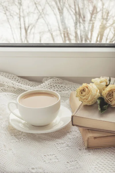 Cup of coffee with milk on windowsill and book with dry rose  as decor on lace. Vintage. — Stock Photo, Image