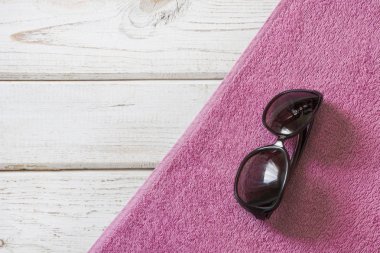 Plaj aksesuarları Beyaz ahşap zemin üzerinde havlu ve yaz. Yukarıdan görüntüleyin. Alay reklam veya ambalaj için boş.