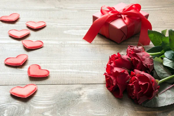 Buquê de rosas vermelhas e presente com fita vermelha e coração na placa de madeira. O cartão do Valentine. Espaço de cópia . — Fotografia de Stock