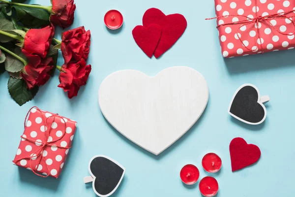 Valentijnsdag kaart. Boeket van rode rozen en gift, hart als leeg voor tekst op blauwe ondergrond. Bovenaanzicht. Kopiëren van ruimte. — Stockfoto