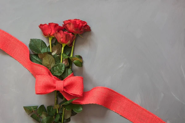Букет красных роз и красной ленты на сером фоне. Открытка Валентина. Закрывай. Копирование пространства . — стоковое фото
