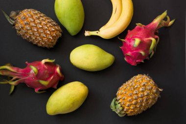 Tropikal meyve ananas, muz, dragon meyve ve mango siyah. Üstten Görünüm. Düz yatıyordu.