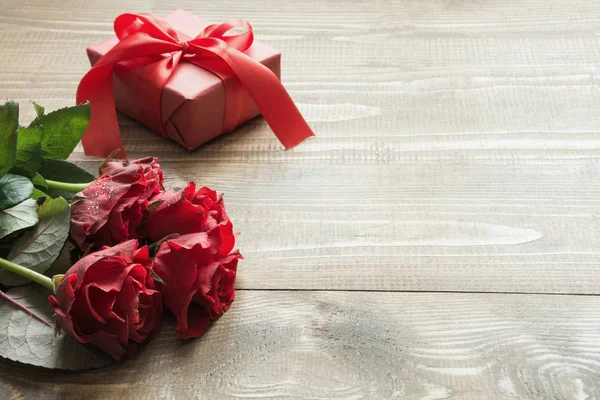 Buquê vermelho rosa flores e caixa de presente na mesa de madeira. Espaço para cópia. Fechar . — Fotografia de Stock