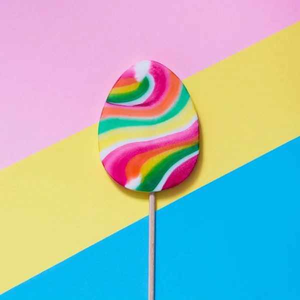 Lollipops dulces como huevo sobre papel colorido. Curioso concepto de Pascua. Vista superior. Imagen cuadrada . — Foto de Stock